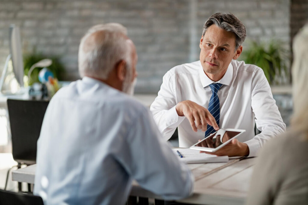Insurance agents using digital tablet while having meeting with senior clients office